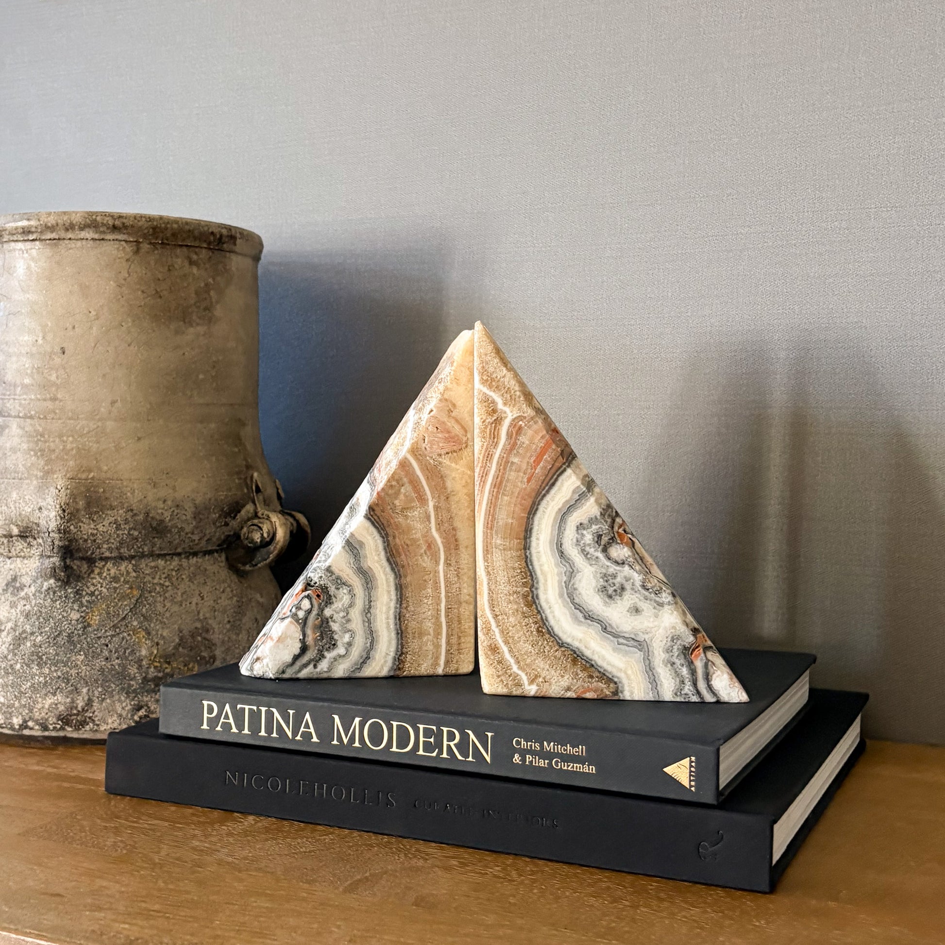 Triangular zebra calcite bookend pair featuring cream, tan and gray veining on stacked coffee table books