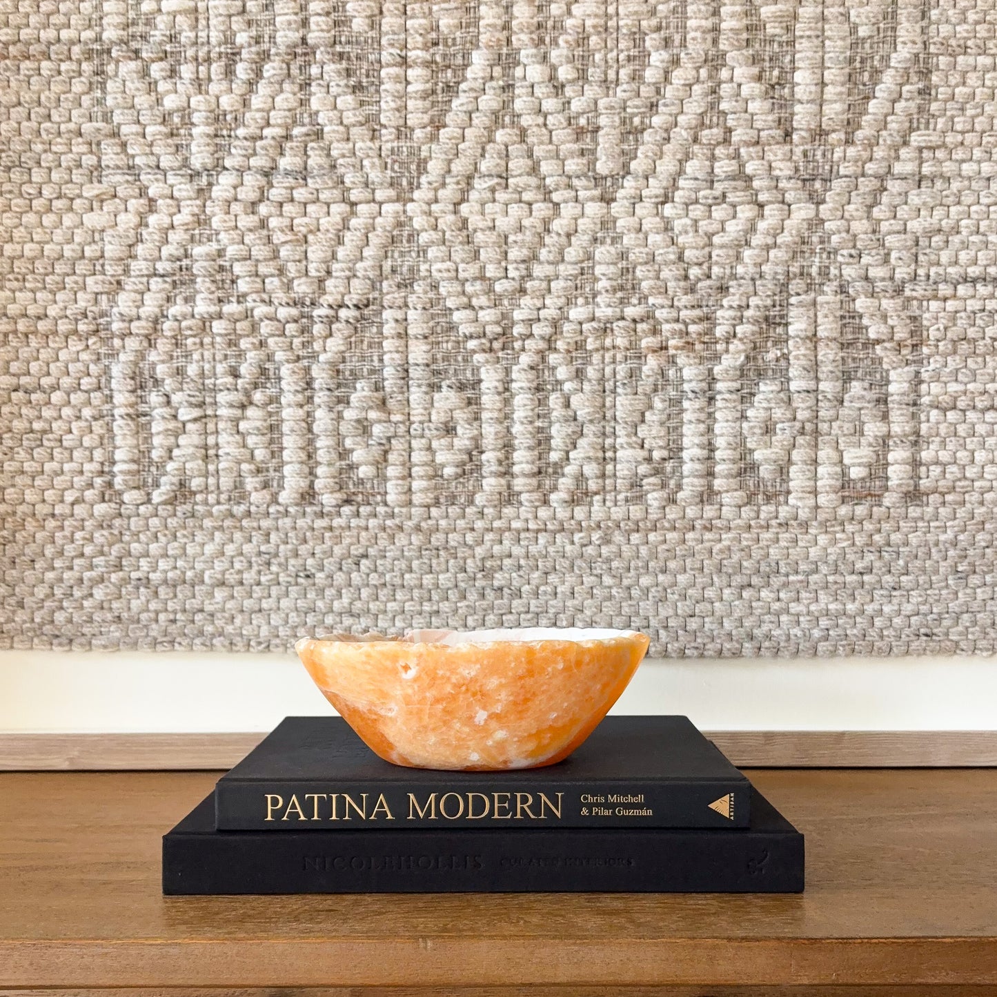 Hand carved zebra calcite bowl with orange honey calcite interior displayed on decorative books for modern home decor