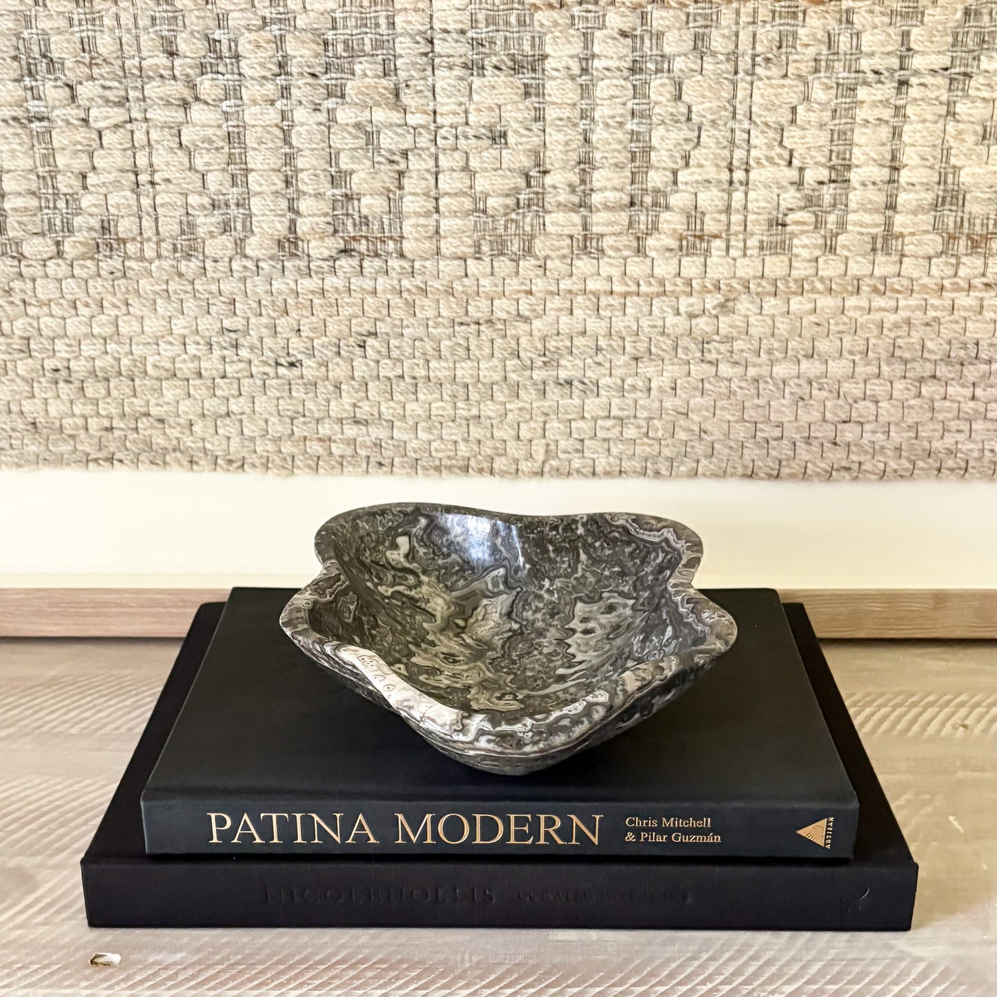 Decorative black and white bowl on a book titled 'Patina Modern' with a textured wall background