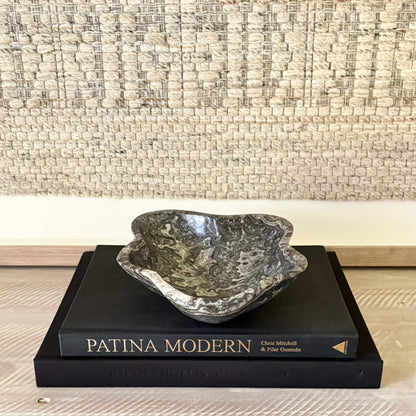 Decorative black and white bowl on a book titled 'Patina Modern' with a textured wall background