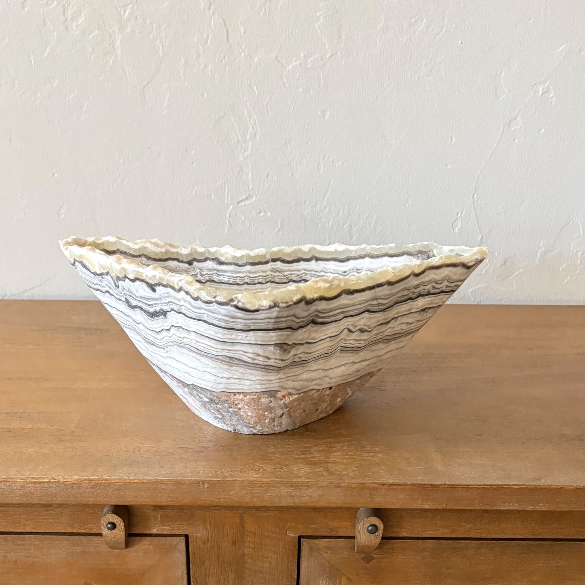 Hand carved zebra onyx decorative bowl with natural black and white stone banding on wood console table